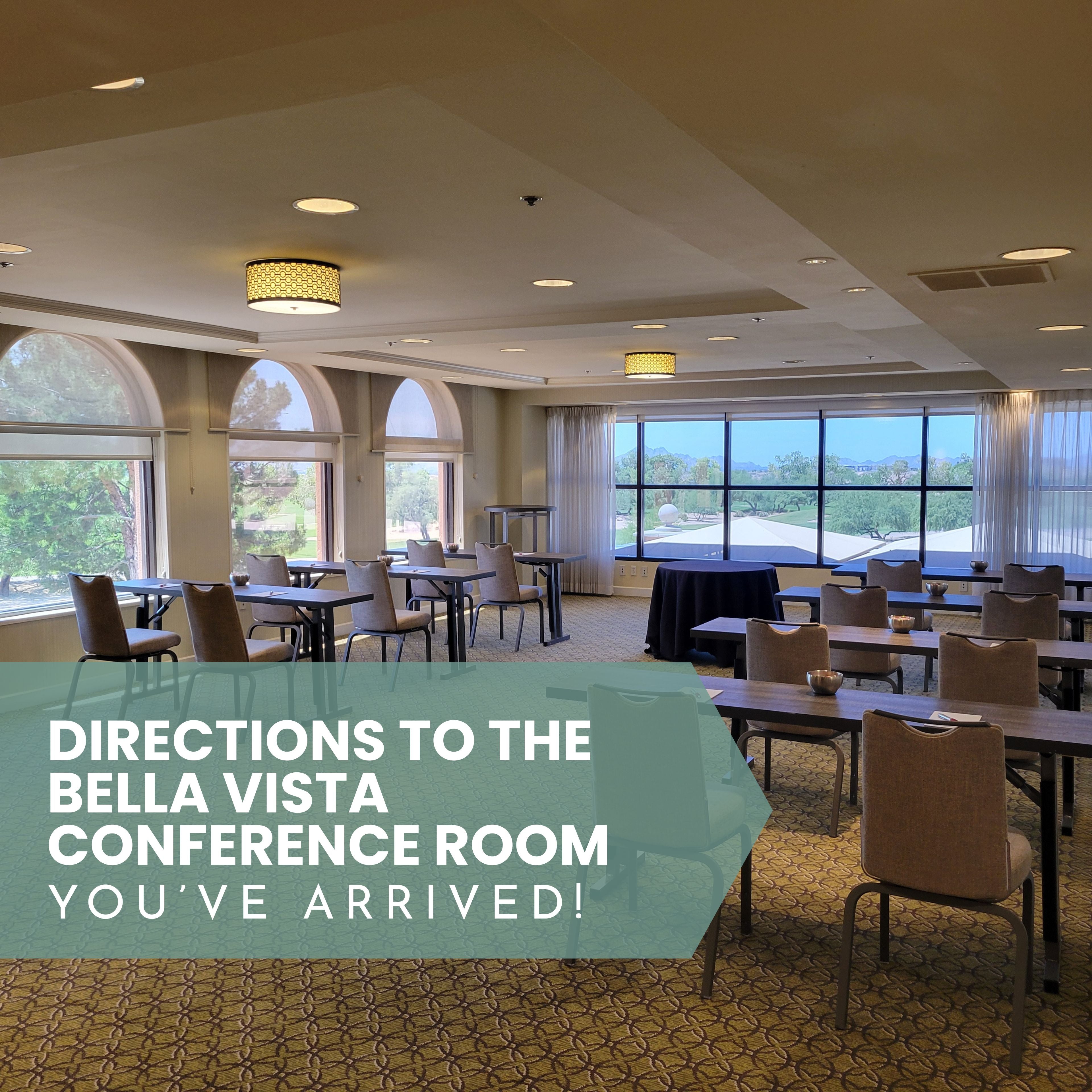 Conference room with tables and chairs, large windows, and text indicating directions to Bella Vista Conference Room.