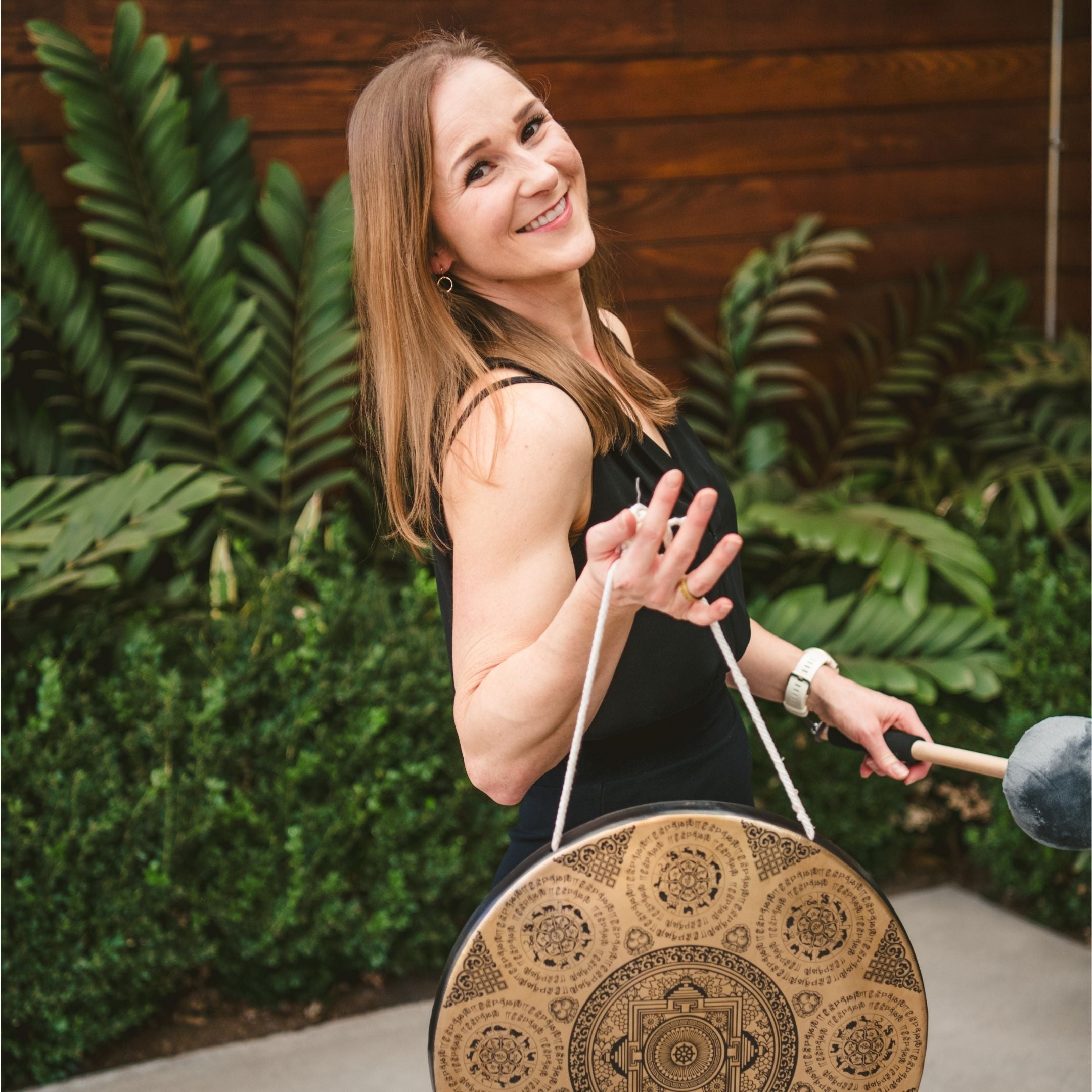 Liz Adriano, Incendify™ Founder, holding a guided meditation instrument outdoors with greenery in the background as a header for her online courses for executives.
