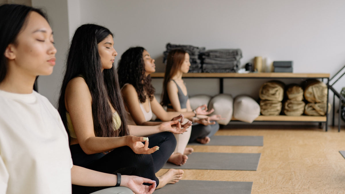 Corporate wellness team building with group of young professionals meditating in the office studio gym.
