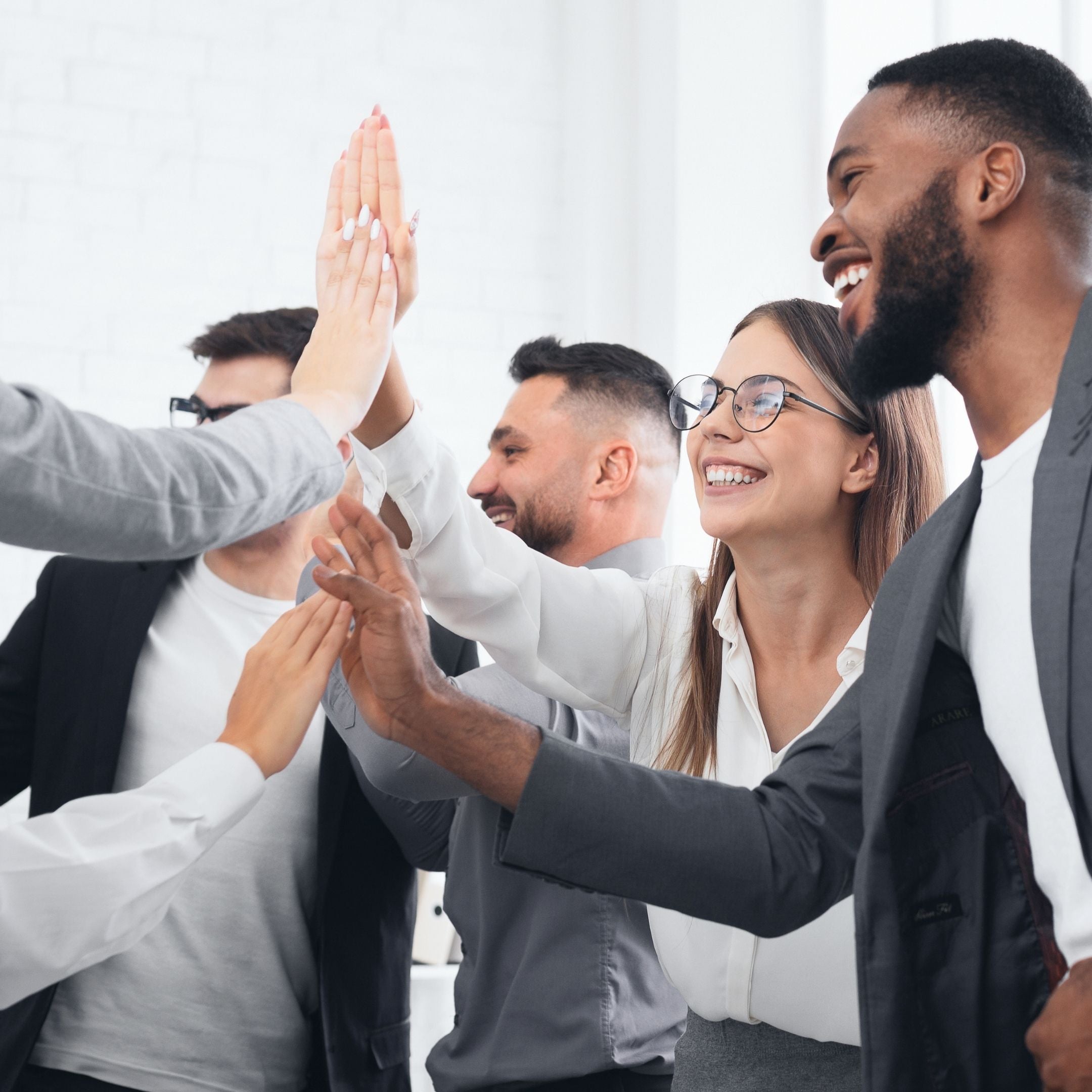 Group of executives giving high fives in an office setting during a team development activity