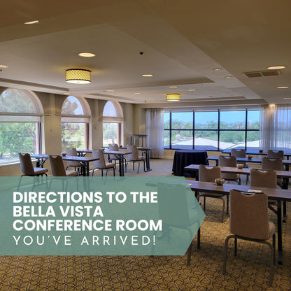 Conference room with tables and chairs, large windows, and text indicating directions to Bella Vista Conference Room.