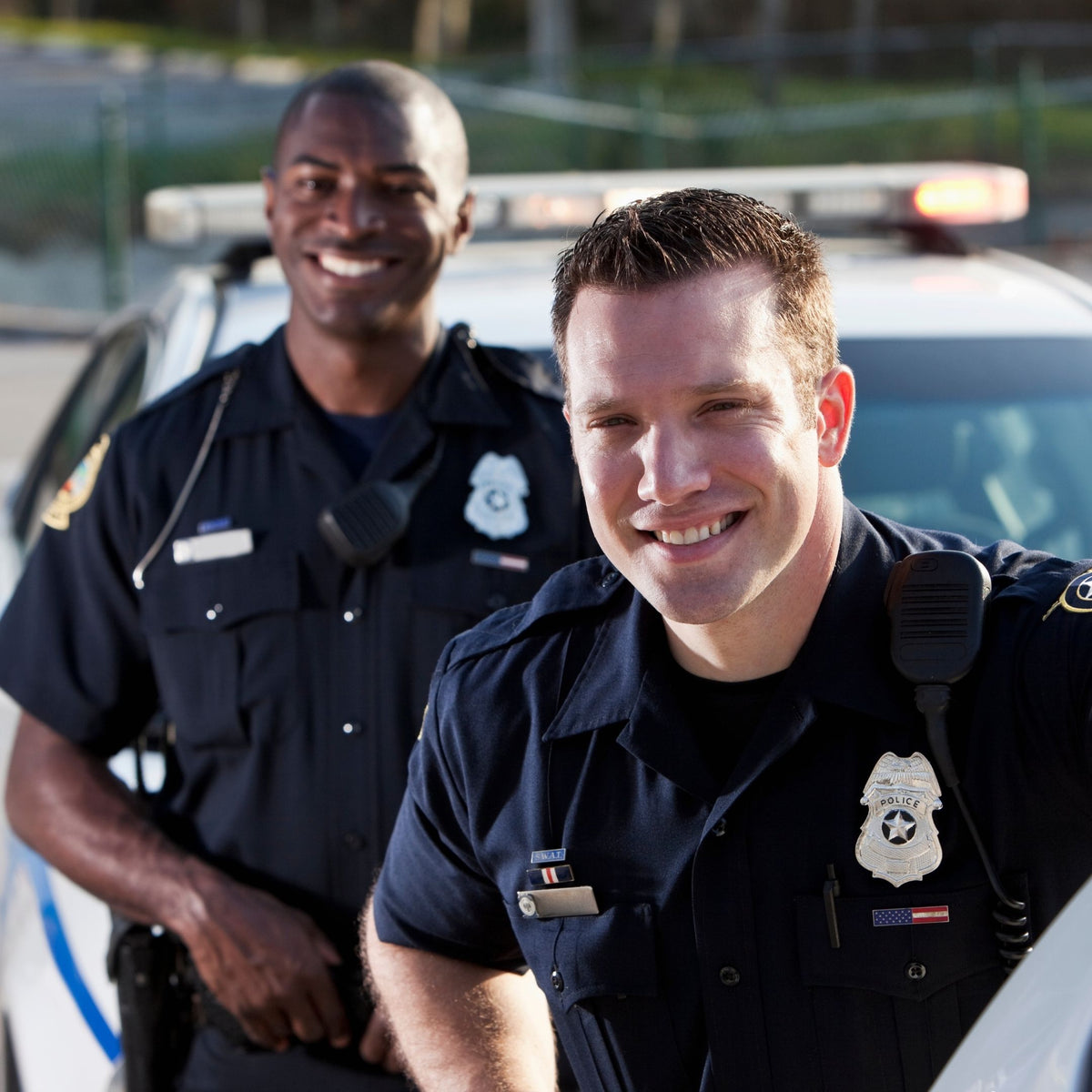 Two police officers standing in front of a police car.